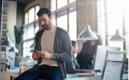 man sitting on a desk while checking his cellphone