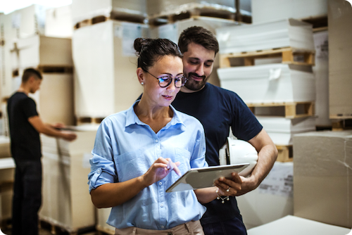 Two workers using a tablet to view shipping savings options for their business.